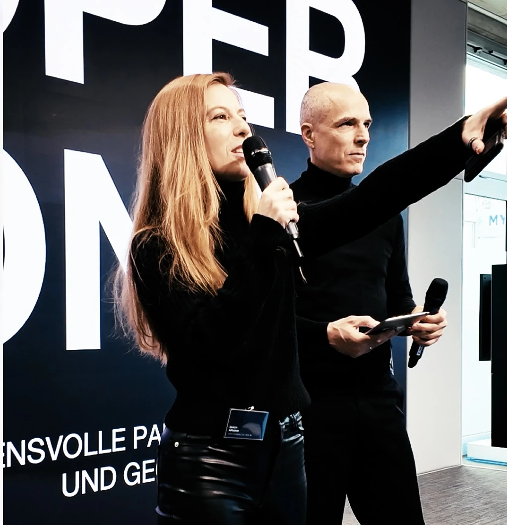 Zwei Personen mit Mikrofonen im Austausch auf einer Bühne zum Thema Kooperationen